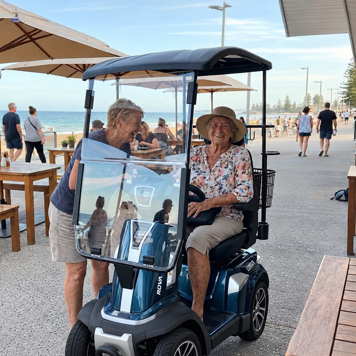 ROVA Elite canopy scooter at seaside cafe with seat-mounted basket and crutch holder